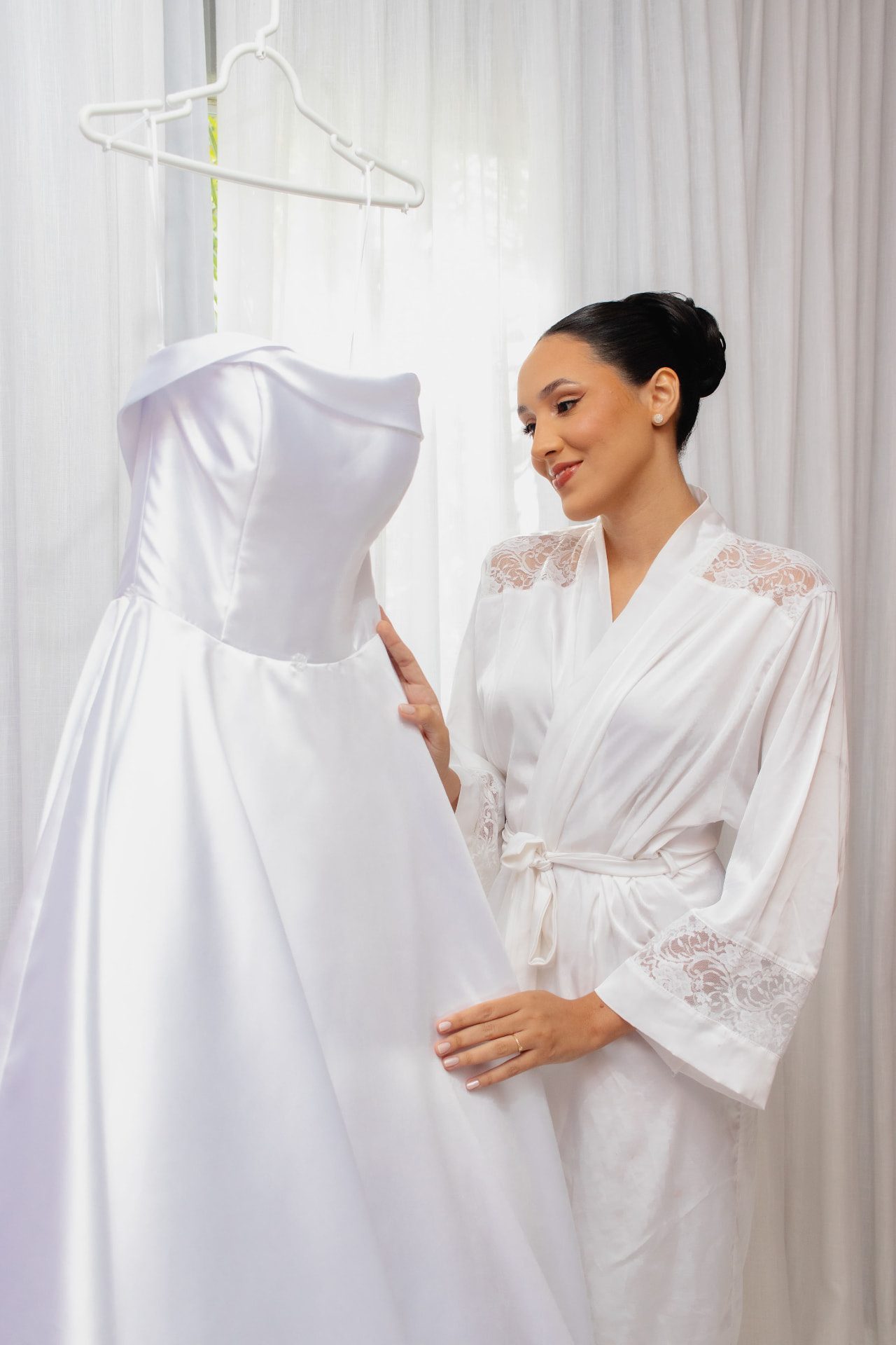 Noiva ao lado do vestido pendurado na sala de preparação